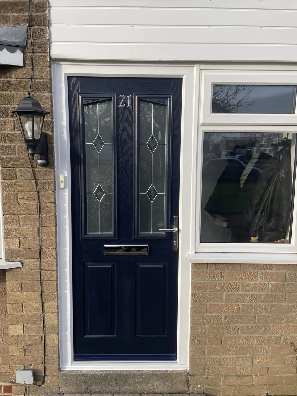 Navy composite front door with leaded glass next to a white uPVC window on a Newcastle house