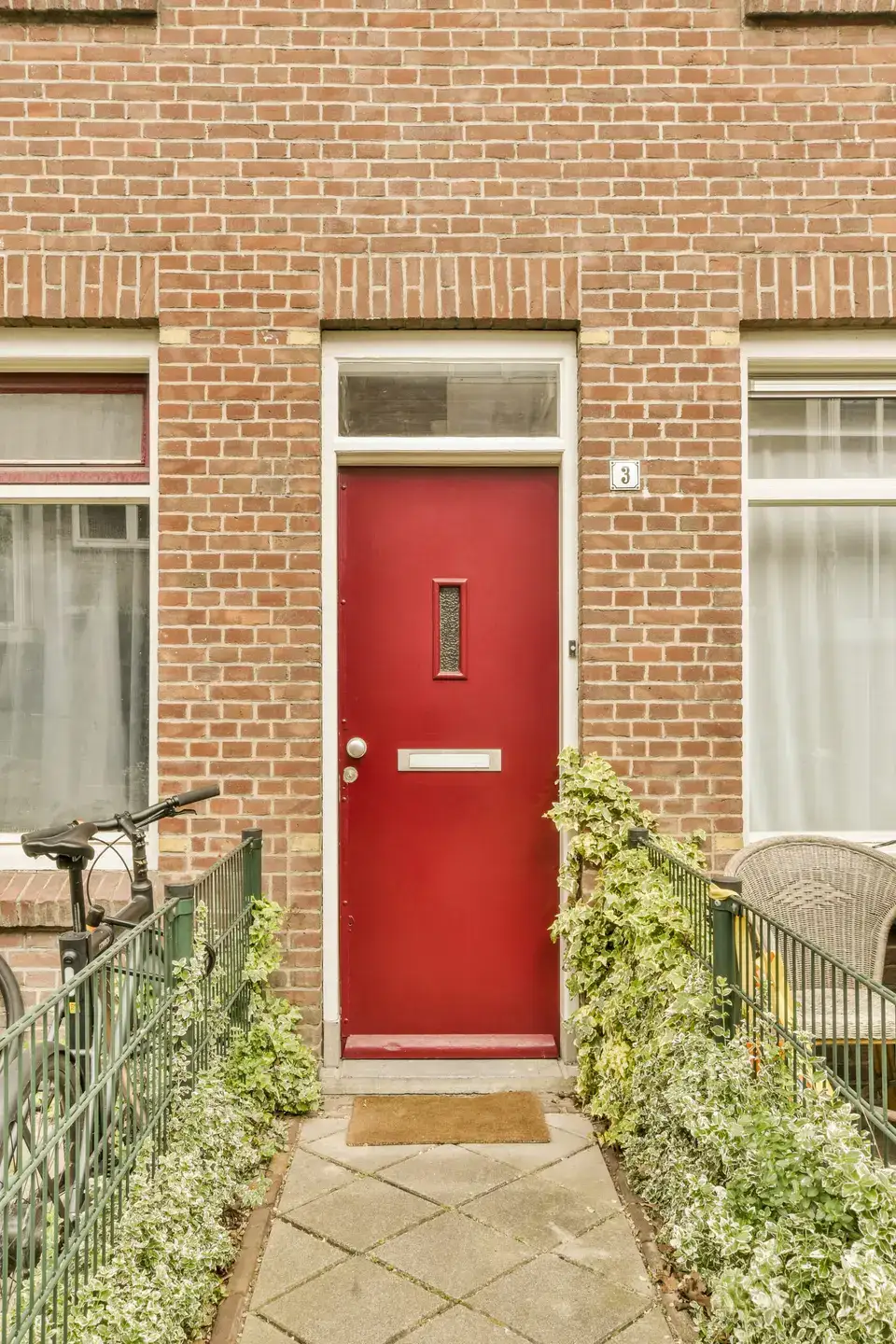 Red front door with a glass transom on a brick terraced house, typical of many Newcastle streets