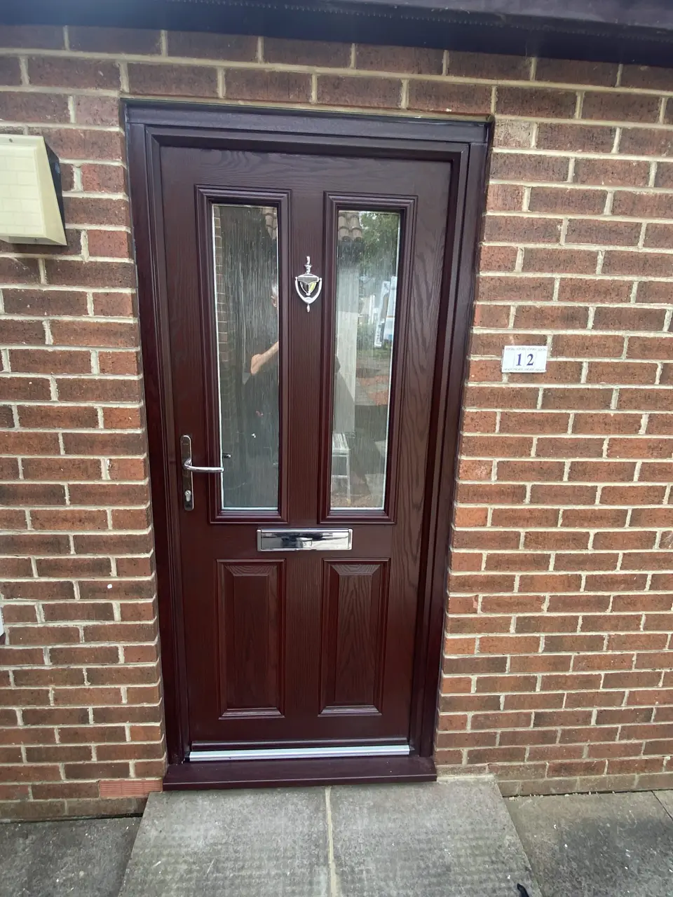Rosewood composite front door with twin glazed panels and chrome handle on a Newcastle home