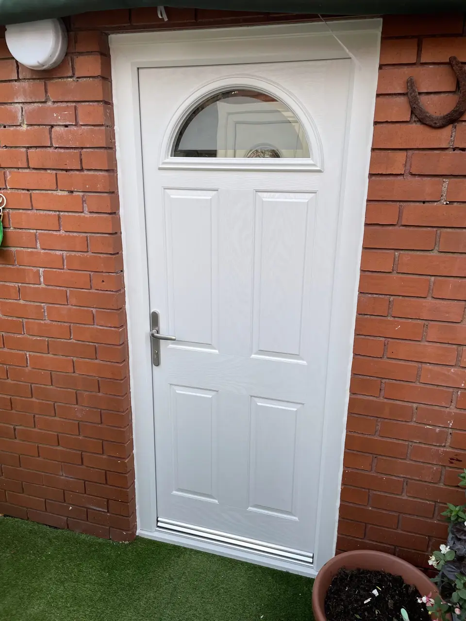 White back door in Newcastle White panelled back door with half-moon glass set in red brickwork in Newcastle