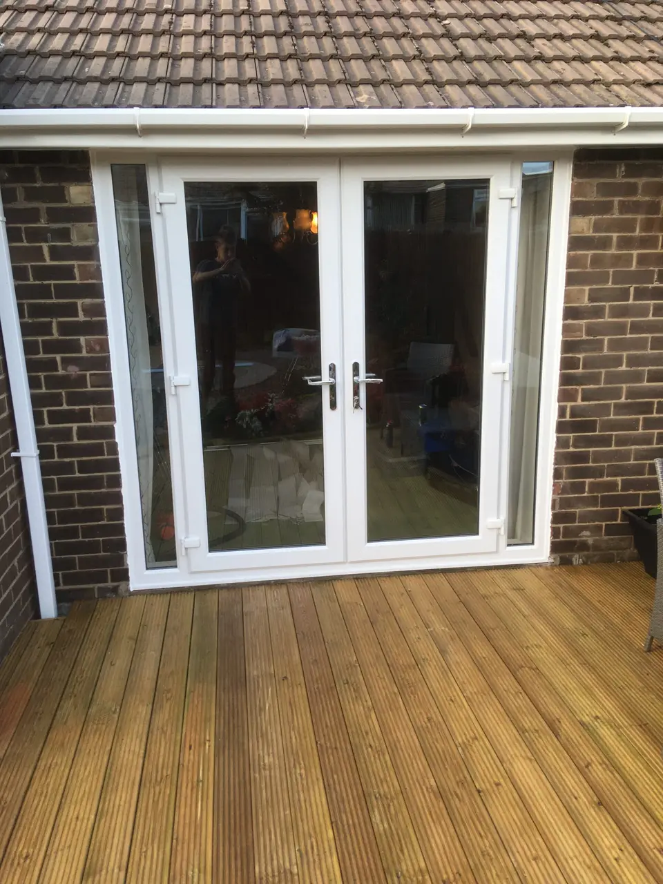 White uPVC French doors in Newcastle White uPVC French doors with side panels opening onto decking at a Newcastle home
